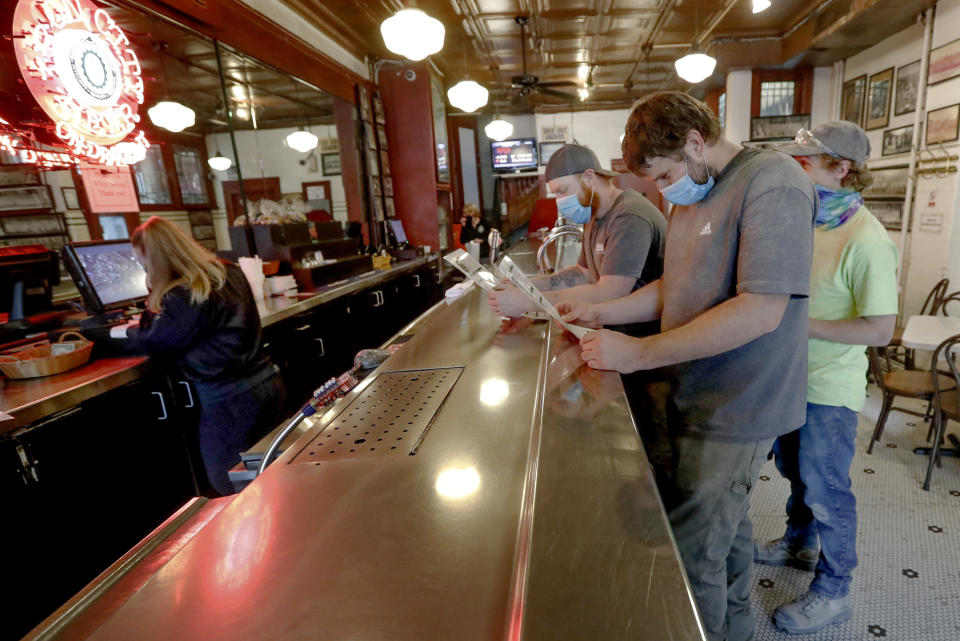 Construction workers Jacob Mooney, center, Corey Bowman, left, and Jason Mooney, right, look over menus at the "Original Oyster House," before ordering fish sandwiches during this year's "1-4-3 Day," Friday, May 22, the 143rd day of 2020, in Pittsburgh. In 2019, Pennsylvania Gov. Tom Wolf declared May 23, 2019, the first "1-4-3 Day," as a day of kindness in honor of Public Broadcasting Service's Fred Rogers, the host of children's program "Mister Rogers' Neighborhood." Rogers, a Pennsylvania native who died in 2003, used 143 as his special code for "I Love You," based on the number of letters in each word. For their part, the restaurant pledged that for every fish sandwich sold, $2 is going to be donated to The American Heart Association. (AP Photo/Keith Srakocic)