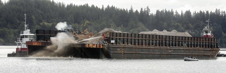 Pacific oyster shells are sluiced from the deck of a barge into the water off the shore of Old Mill Park in Silverdale on Tuesday. Puget Sound Restoration Fund (PSRF) will spread 1,900 cubic yards of shells over up to 20 acres of tidelands, covering them in various densities as they work to restore habitat for the native Olympia oyster in Dyes Inlet.