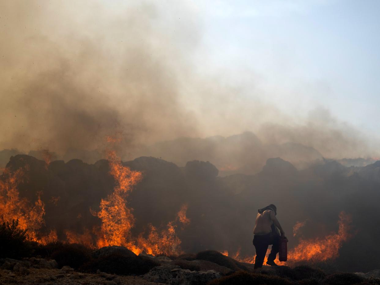 A man tries to extinguish a fire, near the seaside resort of Lindos, on the Aegean Sea island of Rhodes, southeastern Greece (AP)