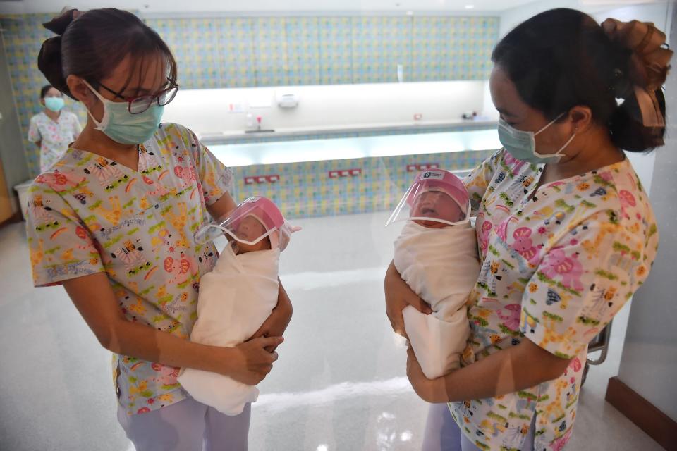 Nurses holding newborn babies wearing face shields at Bangkok's Praram 9 Hospital. (Photo: LILLIAN SUWANRUMPHA via Getty Images)