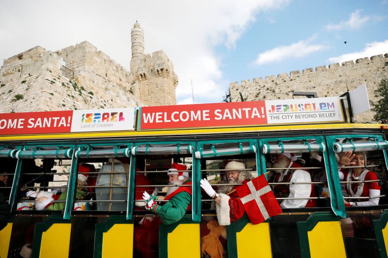 A group of Santa Clauses from around the world, ride a sightseeing vehicle as they make their way into Jerusalem's Old City