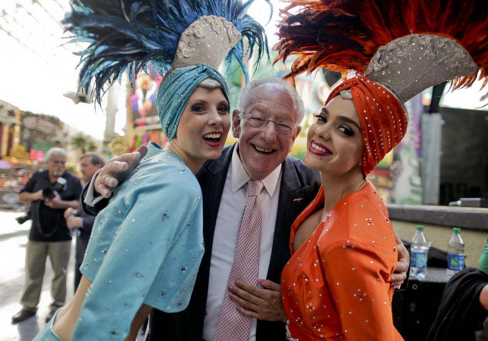 Oscar Goodman poses for photos with two showgirls before kicking off a car show at the Fremont Street Experience, 105Friday, May 17, 2013, in Las Vegas. The former Las Vegas mayor branded the city with a larger than life persona. And now he's branded himself again with a memoir. In “Being Oscar--From Mob Lawyer to Mayor of Las Vegas, Only in America,” Goodman tells all from his days as a lawyer representing members of the mob to his three terms as the “happiest mayor in the universe." (AP Photo/Julie Jacobson)