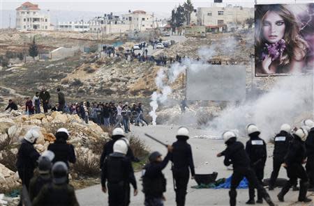 Palestinian policemen (backs to camera) stand in front of demonstrators outside the Jalazoun refugee camp near the West Bank city of Ramallah January 12, 2014. REUTERS/Mohamad Torokman