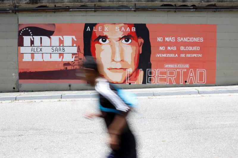 A man goes past a mural in support of the liberation of Colombian businessman and envoy Alex Saab, who is detained in Cape Verde on charges of laundering money for the government of Venezuelan President Nicolas Maduro, in Caracas