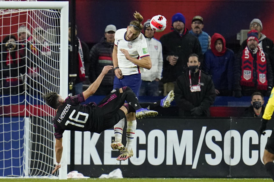 Mexico's Hector Herrera (16) attempts a scissors kick as United States' Walker Zimmerman heads the ball out of danger during the first half of a FIFA World Cup qualifying soccer match, Friday, Nov. 12, 2021, in Cincinnati. The U.S. won 2-0. (AP Photo/Julio Cortez)