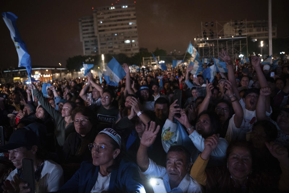 People watch the inauguration ceremony of incoming Guatemalan President Bernardo Arevalo on a screen outside the National Palace in Guatemala City, early Monday, Jan. 15, 2024. (AP Photo/ Santiago Billy)