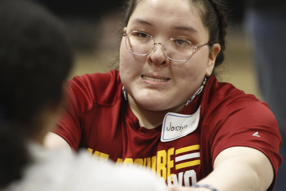 Jordyn Hoffman, of Mount Edgecumbe High School in Sitka, Alaska, scrunches her face as she participates in the Eskimo stick pull at the Native Youth Olympics Friday, April 26, 2024, in Anchorage, Alaska. The Native Youth Olympics is a statewide competition that attracts hundreds of Alaska Native athletes each year and pays tribute to the skills and techniques used by their ancestors to survive in the harsh polar climate. (AP Photo/Mark Thiessen)