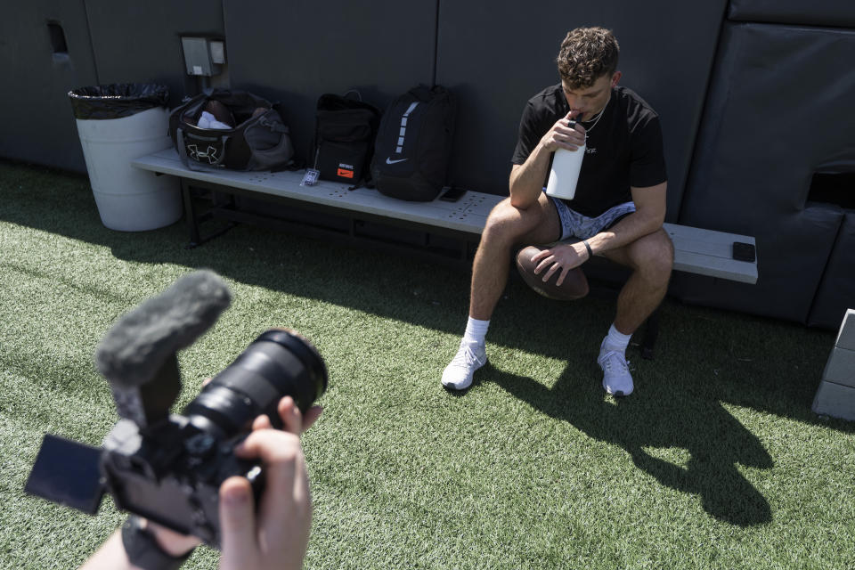 Adam Botkin a football TikTok influencer, records a video for a TikTok post at Washington-Grizzly Stadium in Missoula, Mont., on Monday, May 1, 2023. Botkin, a former walk-on place kicker and punter for the Montana Grizzlies, gained notoriety on the social media platform after videos of him performing kicking tricks went viral. (AP Photo/Tommy Martino)