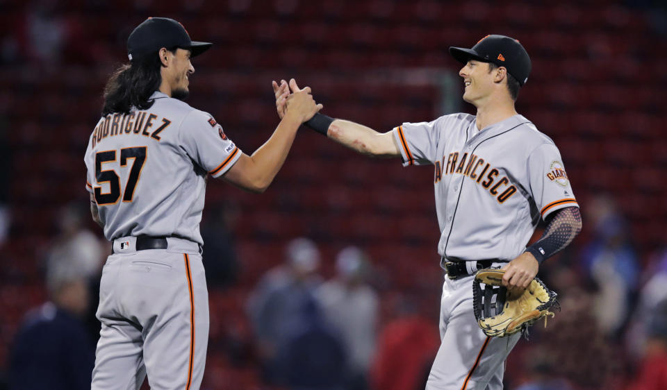 San Francisco Giants relief pitcher Dereck Rodriguez (57) and left fielder Mike Yastrzemski, right, celebrate after the Giants defeated the Boston Red Sox in 15 innings during a baseball game at Fenway Park in Boston, early Wednesday, Sept. 18, 2019. Yastrzemski homered and Rodriguez got the win in the 7-6 victory. (AP Photo/Charles Krupa)