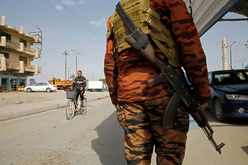 An Iraqi policeman carries a weapon at a checkpoint in Falluja