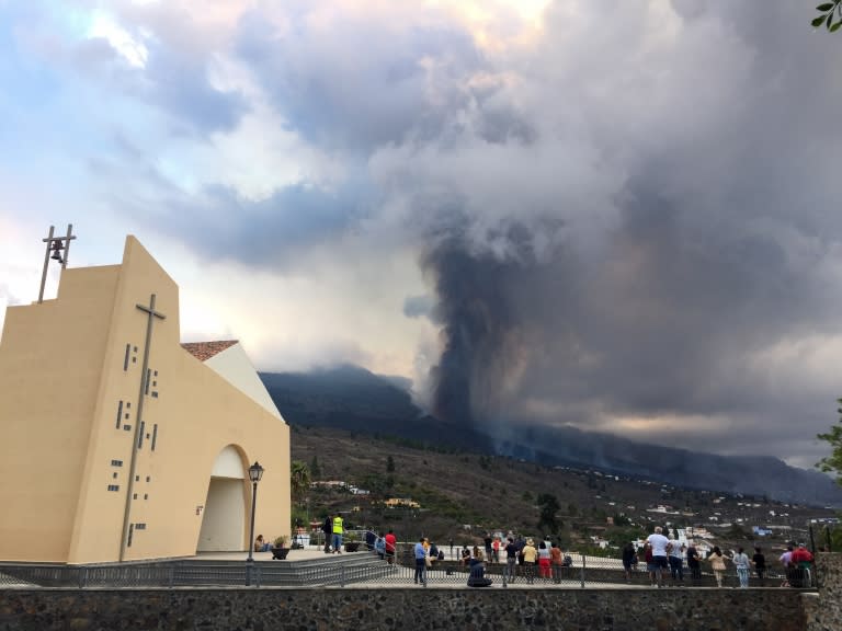 Una iglesia, personas y la columna del volcán La Palma de fondo.