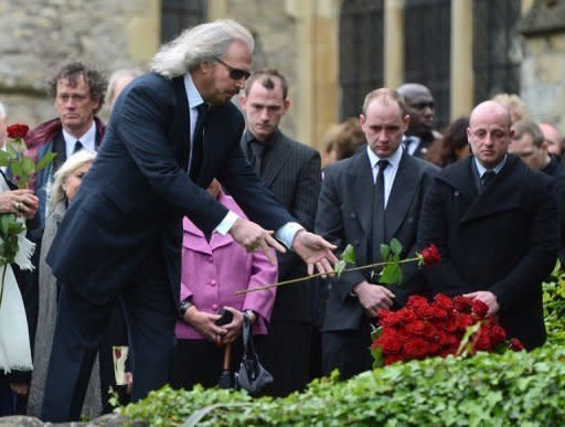Bee Gee Barry Gibb, brother of Robin Gibb, drops a rose onto his brother's grave during a funeral service at St Mary's Church in Thame, central England, on June 8. The sole surviving member of the Bee Gees paid tribute to his bandmate and brother Robin at his funeral on Friday, mourning the loss of his "magnificent mind and his beautiful heart"