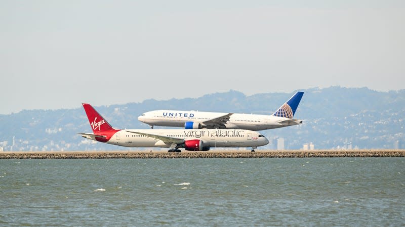 2023 Flight Cancellations: A United jet aircraft lands just as a Virgin Atlantic jet prepares for take off on a tarmac near the Pacifica ocean in San Francisco.