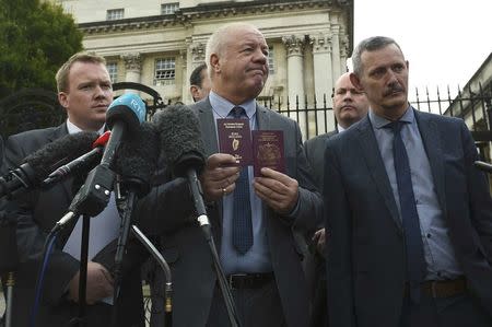 Raymond McCord (C) displays his Irish and United Kingdon passports to media as he departs the High Court in Belfast, Northern Ireland October 28, 2016. REUTERS/Clodagh Kilcoyne