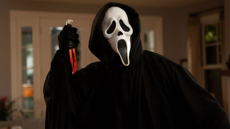 Masked murderer holds a bloody knife in a still from Scream movie.