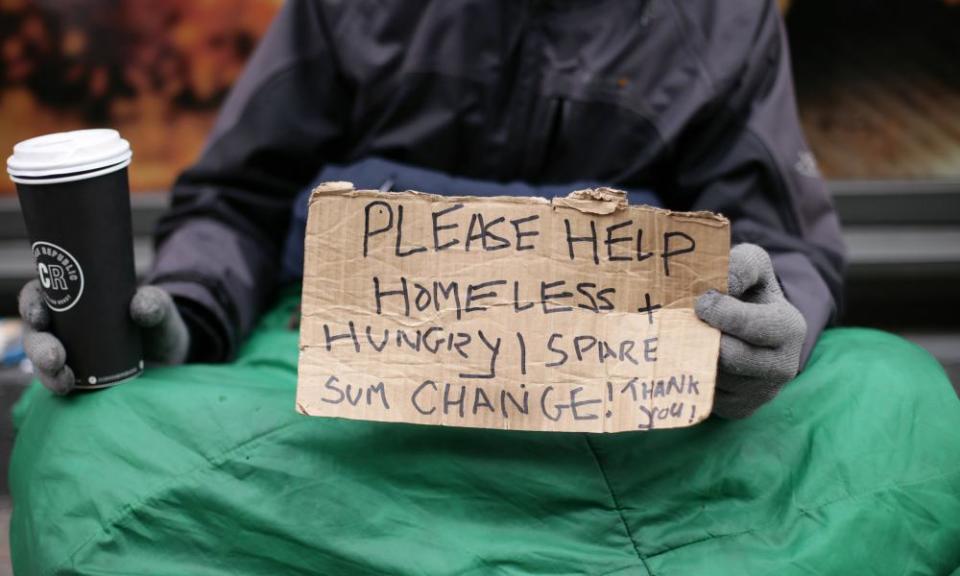 Homeless person holds out sign asking for money.