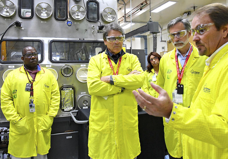 FILE - In this May 10, 2017, file photo provided by the Los Alamos National Laboratory, U.S. Secretary of Energy Rick Perry, second from left, accompanied by Laboratory Director Charlie McMillan, second from right, learns about capabilities at the Los Alamos laboratory's Plutonium Facility, from Jeff Yarbrough, right, Los Alamos Associate Director for Plutonium Science and Manufacturing, in Los Alamos, N.M. A Nevada congressman called for U.S. Energy Secretary Rick Perry’s resignation Wednesday, July 10, 2019, after the department acknowledged dozens of shipments of low-level radioactive waste shipped to a site north of Las Vegas may have been mislabeled and out of compliance with safety regulations for years. (Los Alamos National Laboratory via AP, File)