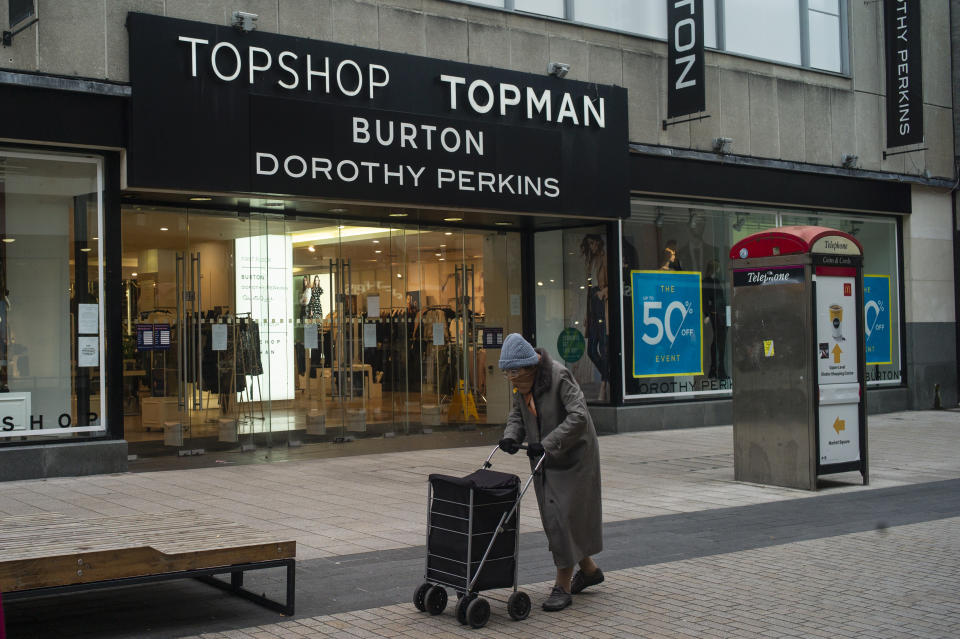 LONDON, ENGLAND - NOVEMBER 30: An elderly woman wearing a face mask walks past a store encompassing Topshop, Topman, Burton and Dorothy Perkins on November 30, 2020 in London, England. Sir Philip Green's retail empire Arcadia, which includes Topshop, Burton, Dorothy Perkins, Evans and Wallis is facing entering administration today putting 13,000 jobs at risk. (Photo by Dan Kitwood/Getty Images)