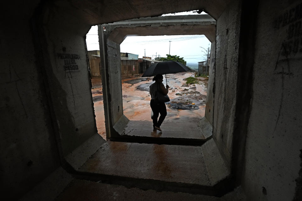A resident walks between concrete structures after it rained in the Sol Nascente favela of Brasilia, Brazil, Tuesday, March 21, 2023. Sol Nascente, which means Rising Sun, suffers poor public transport and has unpaved, impassable roads, which flood frequently during the months of summer rains. (AP Photo/Eraldo Peres)