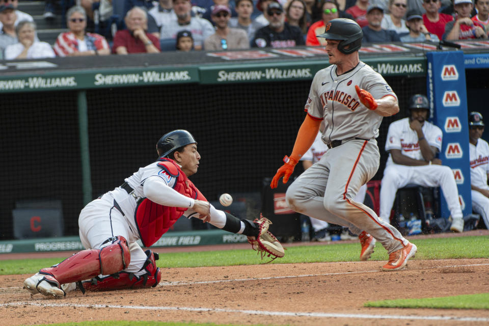 Cleveland Guardians' catcher Bo Naylor, left, misses the throw as San Francisco Giants' Matt Chapman slides safely into home plate during the fifth inning of a baseball game in Cleveland, Saturday, July 6, 2024. (AP Photo/Phil Long)