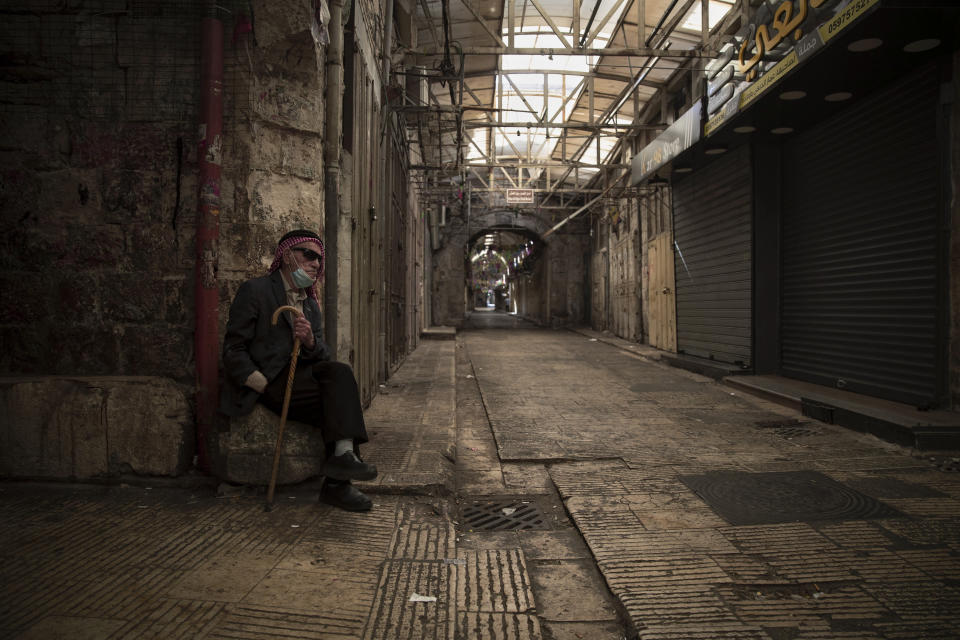 A Palestinian man sits in front of closed shops during a general strike, in the West Bank city of Nablus, Tuesday, May 18, 2021. Palestinian leaders are calling for a general strike in Gaza, the West Bank and within Israel to protest against Israel's air strikes on Gaza and the violent confrontations between Israeli security forces and Palestinians in Jerusalem. (AP Photo/Majdi Mohammed)