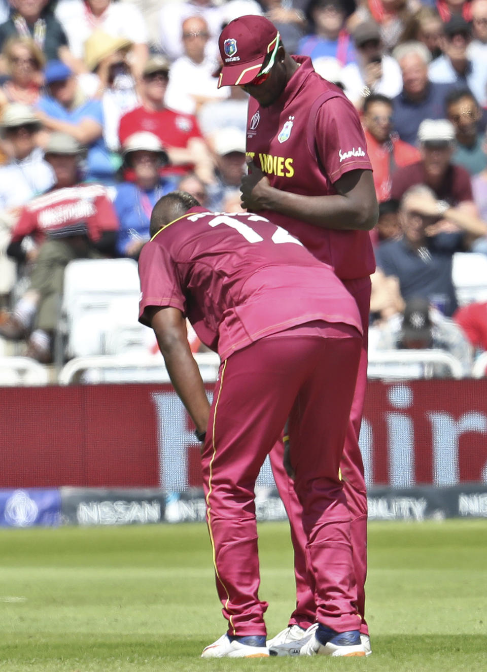 West Indies' captain Jason Holder, right, attend to teammate Andre Russell before he walked off the filed during the Cricket World Cup match between Australia and West Indies at Trent Bridge in Nottingham, Thursday, June 6, 2019. (AP Photo/Rui Vieira)