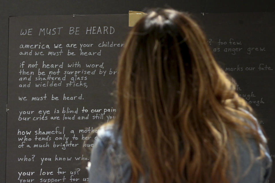 A visitor reads a poem displayed at a new exhibit, "Twin Flames: The George Floyd Uprising from Minneapolis to Phoenix," at Arizona State University Art Museum, in Tempe, Arizona on Friday, Feb. 2, 2024. For months after George Floyd was killed by police in May 2020, people from around the world traveled to the site of his murder in Minneapolis and left signs, paintings and poems to memorialize the man whose death reignited a movement against systemic racism. Now hundreds of those artifacts are being displayed at an exhibit at the Arizona State University Art Museum. (AP Photo/Cheyanne Mumphrey)