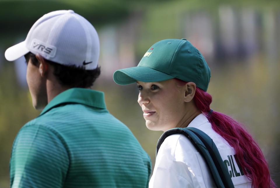 Rory McIlroy, of Northern Ireland, walks with his fiancee and tennis player Caroline Wozniacki after Wozniacki putted on the ninth hole during the par three competition at the Masters golf tournament Wednesday, April 9, 2014, in Augusta, Ga. (AP Photo/David J. Phillip)