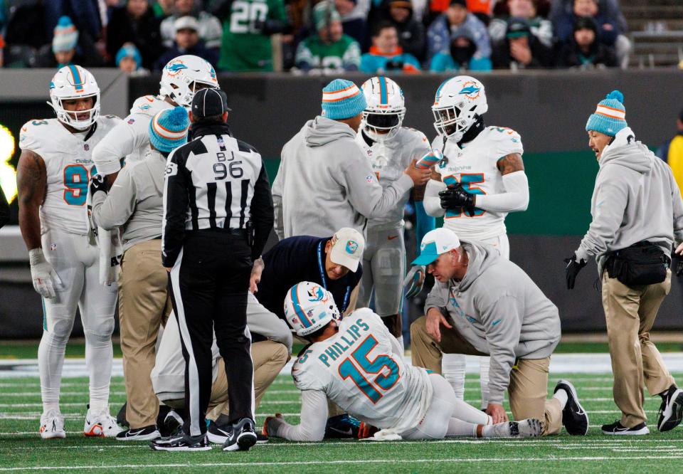 Miami Dolphins linebacker Jaelan Phillips (15) is being treated by team medical personnel after getting injured in a play during fourth quarter of an NFL football game against the New York Jets, Friday, Nov. 24, 2023, in East Rutherford, N.J. (David Santiago/Miami Herald via AP)