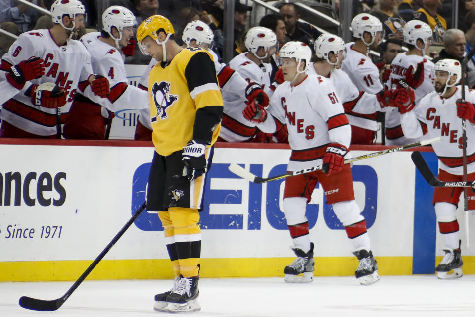 Pittsburgh Penguins' Brian Dumoulin, left, skates to the bench as Carolina Hurricanes' Jake Gardiner (51) is greeted by teammates after giving his team the lead with a goal during the second period of an NHL hockey game, Sunday, March 8, 2020, in Pittsburgh. (AP Photo/Keith Srakocic)
