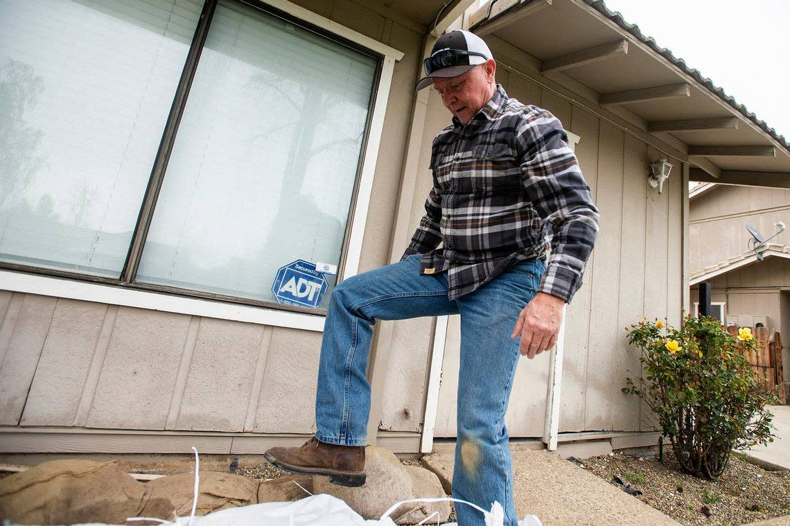 Chief Operating Officer of Leap Carpenter Kemps Insurance, Dave Cribb, 64, of Oakdale, places sandbags along the front of the home of one of the company’s employees on Driftwood Drive, while preparing for upcoming rainstorms in Merced, Calif., on Thursday, March 9, 2023. According to the resident, the home took on about five inches of water during the previous heavy rains and flooding.