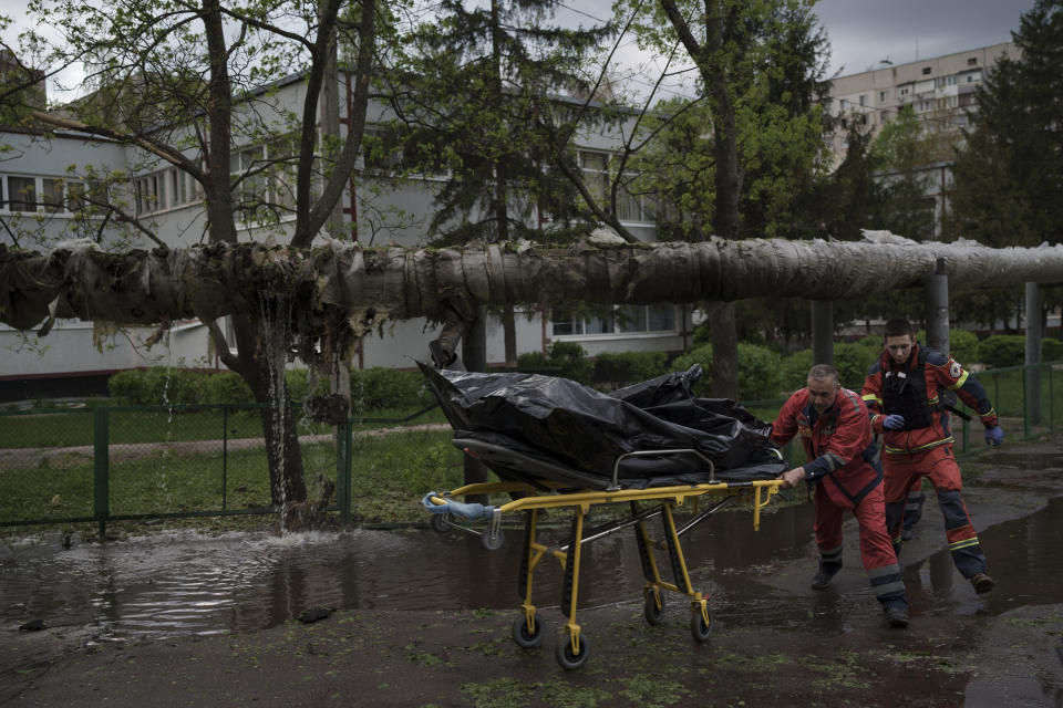 Emergency workers remove the body of a man killed during a Russian bombardment in Kharkiv, Ukraine, Wednesday, April 27, 2022. (AP Photo/Felipe Dana)