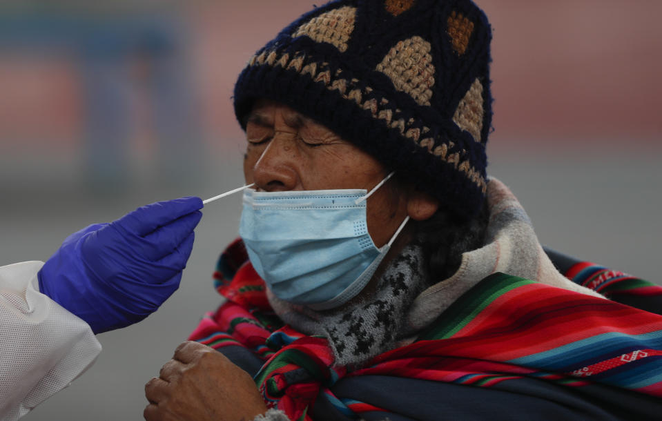 A health worker collects a sample from a resident during testing for the new coronavirus at a sports facility in La Paz, Bolivia, Friday, Jan. 8, 2021. (AP Photo/Juan Karita)