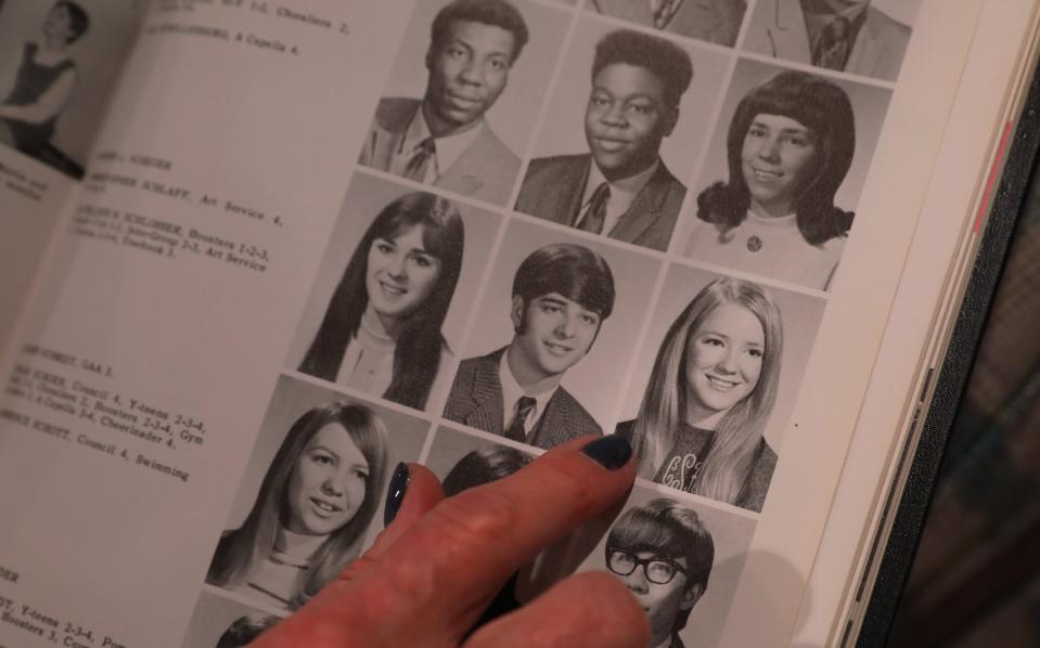 Cathy Behe looks over high school yearbooks, pointing at a photo of her friend Cathleen Schlosser, during an interview in her home in Mount Clemons, Michigan, Wednesday, Dec. 4, 2019.  Cathleen was murdered in February 1982 in Brighton. Her husband James Krauseneck was charged with her murder in November of this year.