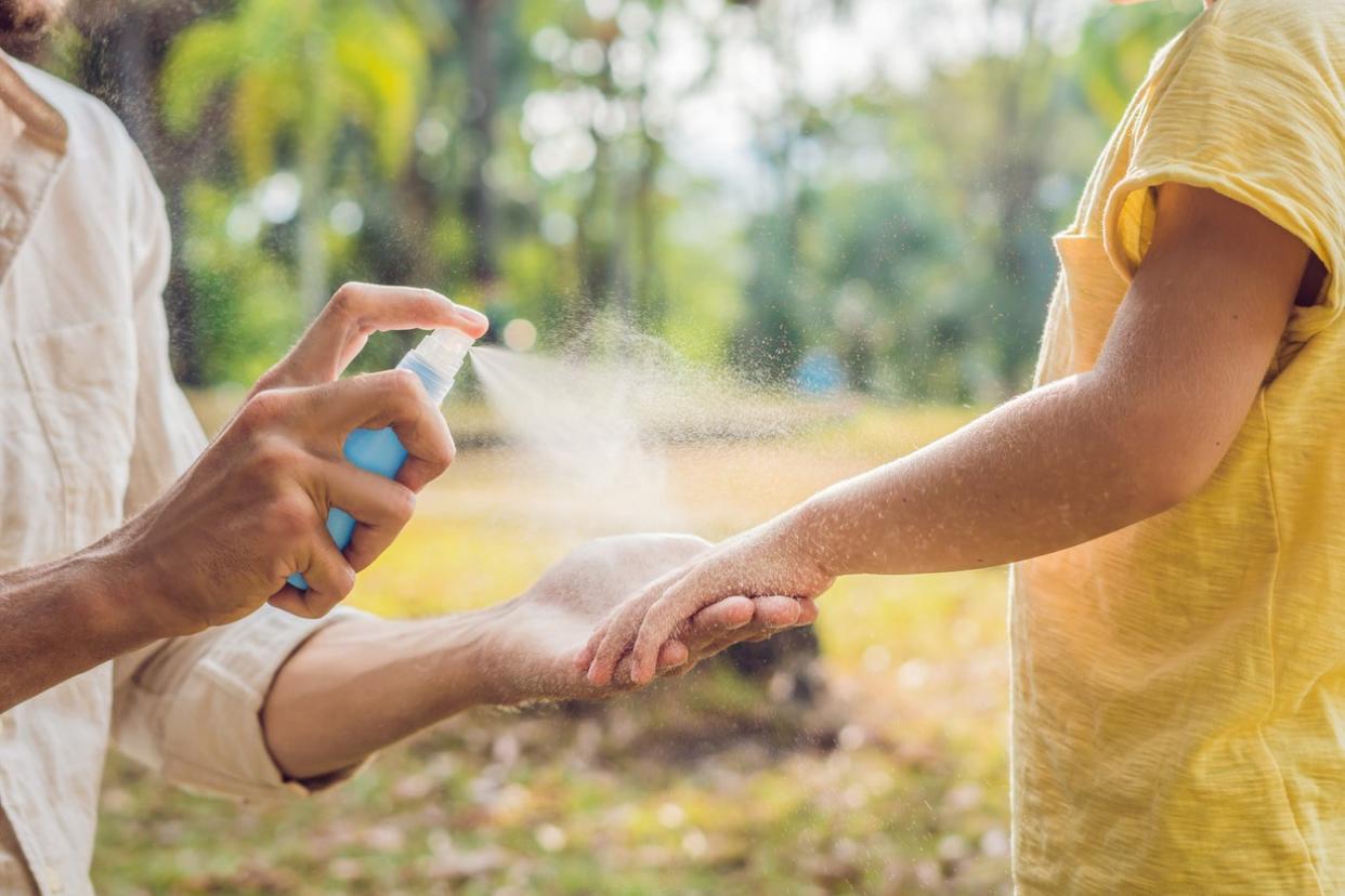 dad and son use mosquito spray.Spraying insect repellent on skin outdoor