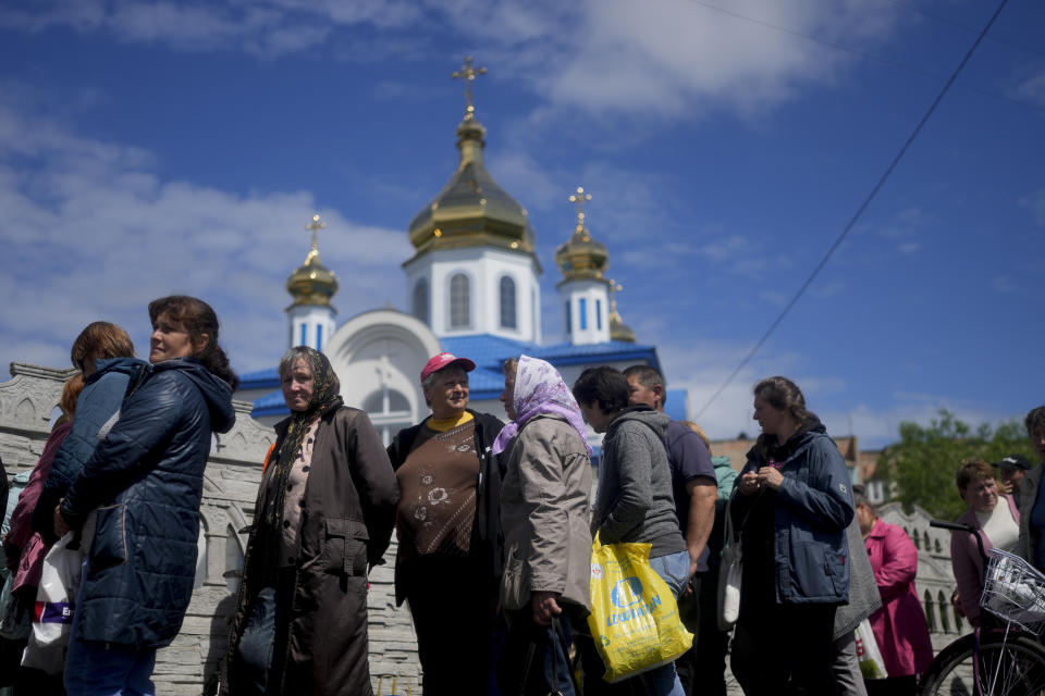 People line up outside a Church to get food and clothing in Borodyanka, on the outskirts of Kyiv, Ukraine, Tuesday, May 31, 2022. (AP Photo/Natacha Pisarenko)