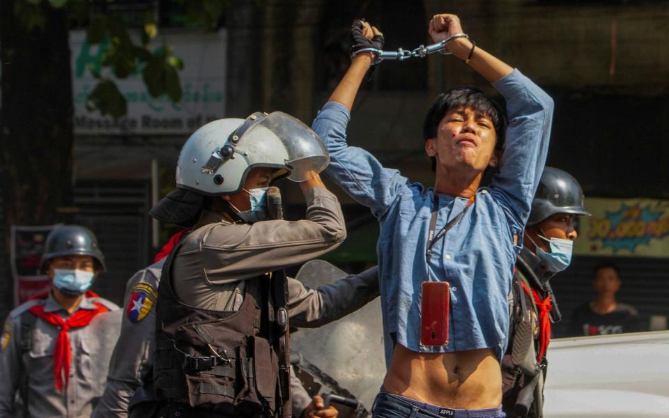 A pro-democracy protester is detained by riot police officers during a rally against the military coup in Yangon