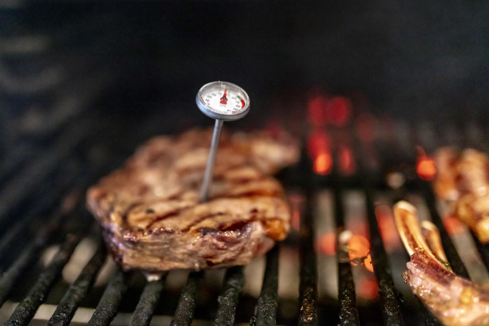 Meat thermometer stuck into steak on the grill