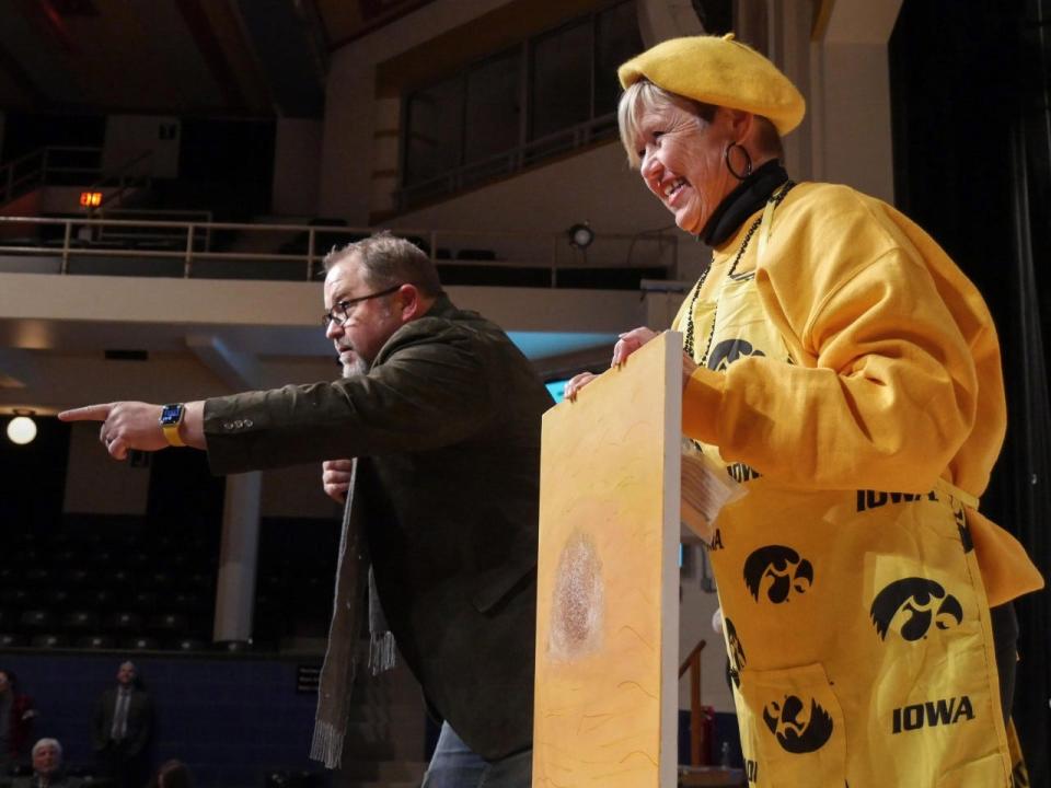 Celebrity Battle of the Brushes emcee KC Fleming auctions off a painting by Burlington celebrity Kim Staub at Burlington Memorial Auditorium on Friday, Nov. 18, 2022. Staub’s painting sold for for $3,000. The event was a fundraiser for event coordinator, the Art Center of Burlington.