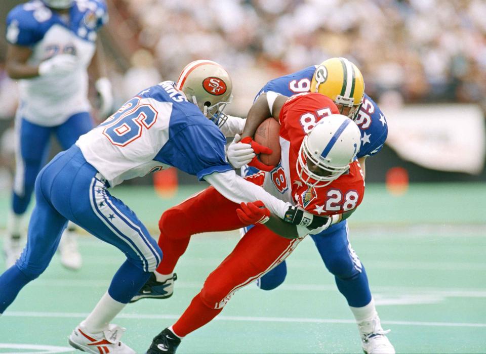 File- This Feb. 5, 1995, file photo shows Baltimore Colts running back Marshall Faulk (28) being pulled down by San Francisco 49ers safety Merton Hanks (36) and Green Bay Packers Bryce Paup during the second quarter of the Pro Bowl in Honolulu. TV ratings for the Pro Bowl lag below all the prime time regular season games, and the on-field intensity and drama that fuels so much of the national interest in the sport is nonexistent. The annual all-star exhibition does not lack for history, however, with a genesis traced back to the 1938 season. (AP Photo/Eric Gay, File)