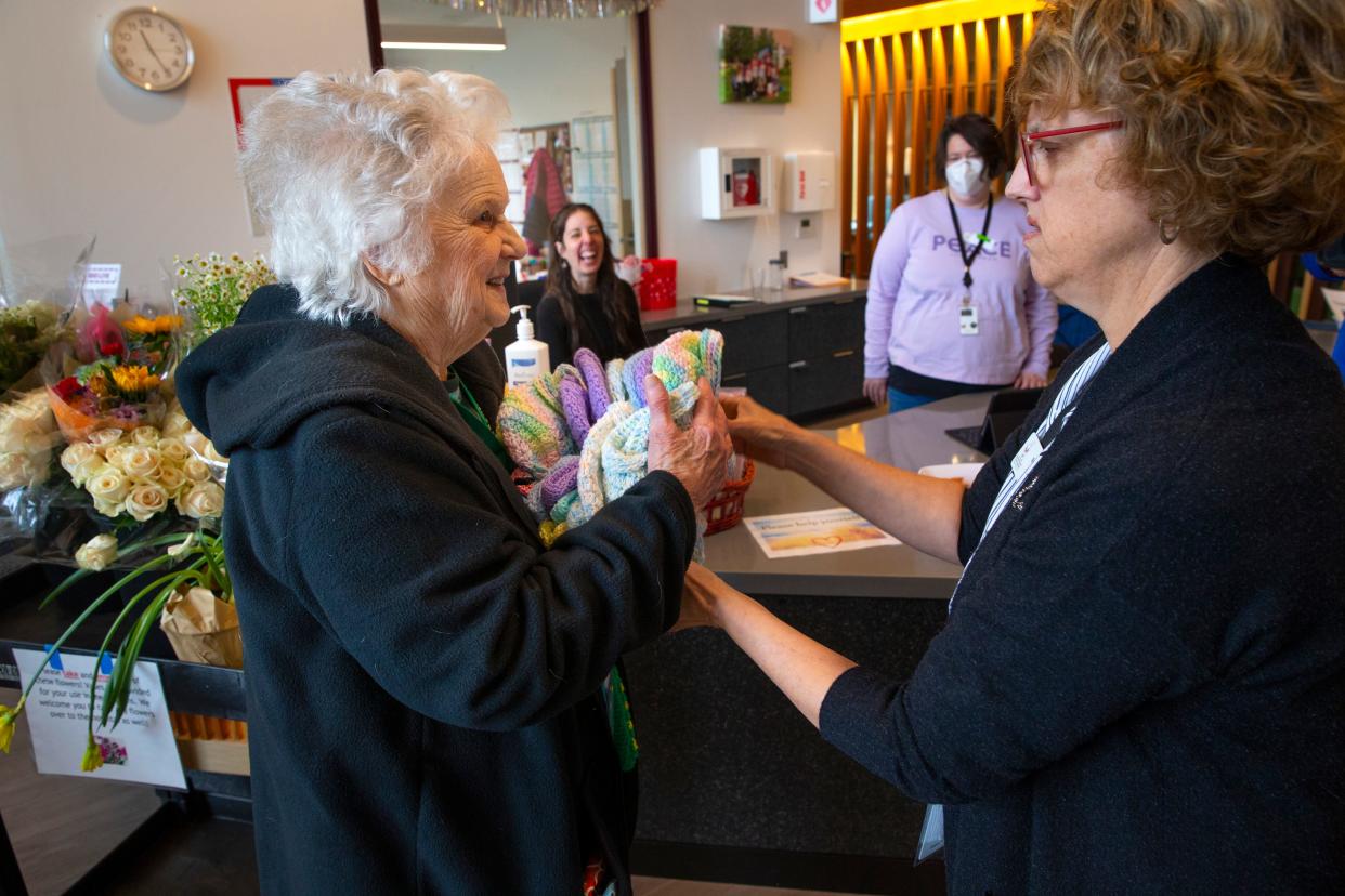 Betty O'Hearn, 93, left, hands an armload of crocheted hats to Robin Yozzo, guest services director of Heartfelt House in Springfield during a visit.