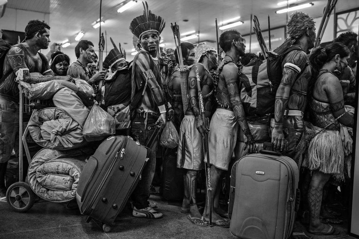 This image provided by World Press Photo, part of a series titled Amazonian Dystopia, by Lalo de Almeida for Folha de Sao Paulo/Panos Pictures which won the World Press Photo Long-Term Project award,, shows Members of the Munduruku community line up to board a plane at Altamira Airport, in Para, Brazil, on 14 June 2013. After protesting at the site of the construction of the Belo Monte Dam on the Xingu River, they traveled to the national capital Brasilia to present their demands to the government. The Munduruku community inhabit the banks of another tributary of the Amazon, the Tapajos River, several hundred kilometers away, where the government has plans to build further hydroelectric projects. Despite pressure from indigenous people, environmentalists and non-governmental organizations, the Belo Monte project was built and completed in 2019. (Lalo de Almeida for Folha de Sao Paulo/Panos Pictures/World Press Photo via AP)