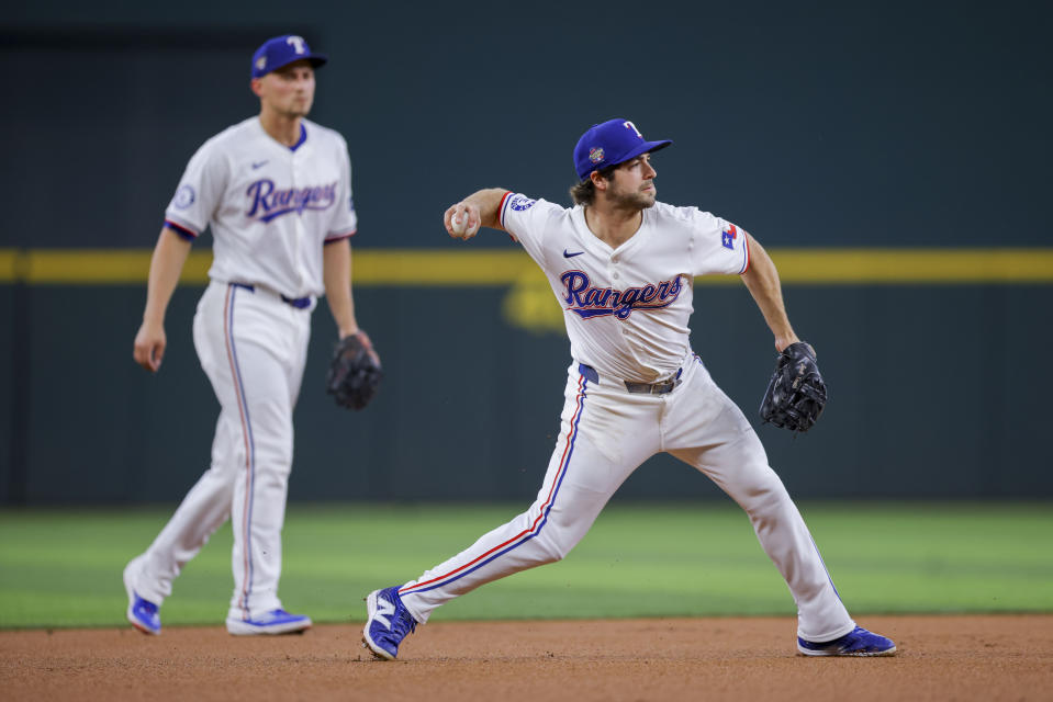 Texas Rangers third baseman Josh Smith, right, fields a ground ball and throws out Cincinnati Reds' Spencer Steer at first base during the first inning of a baseball game in Arlington, Texas, Saturday, April 27, 2024. (AP Photo/Gareth Patterson)