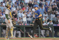 Seattle Mariners' Cal Raleigh, right, scores on a double by teammate Ty France as Oakland Athletics catcher Shea Langeliers, left, looks on during the fourth inning of a baseball game, Friday, May 10, 2024, in Seattle. (AP Photo/Jason Redmond)