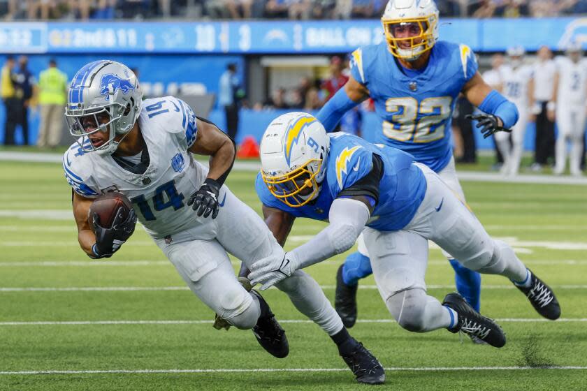 Inglewood, CA, Sunday, November 12, 2023 - Detroit Lions wide receiver Amon-Ra St. Brown (14) slips the tackle of Los Angeles Chargers linebacker Kenneth Murray Jr. (9) during second half action at SoFi Stadium. (Robert Gauthier/Los Angeles Times)