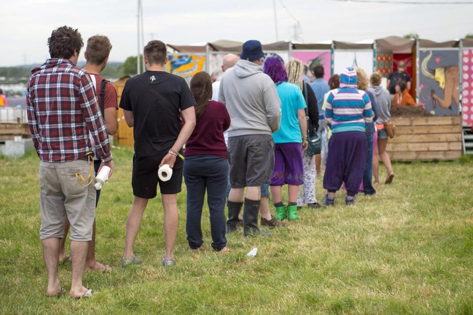 Festival goers queue for the 'long drop' toilet facilities at the Glastonbury Festival, (PA)