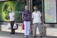 Elderly residents wearing masks to curb the spread of the coronavirus wait at a bus stop with a map of Beijing near a neighborhood under lockdown in Beijing Tuesday, June 16, 2020. Chinese authorities locked down a third neighborhood in Beijing on Tuesday as they rushed to prevent the spread of a new coronavirus outbreak that has infected more than 100 people in a country that appeared to have largely contained the virus. (AP Photo/Ng Han Guan)