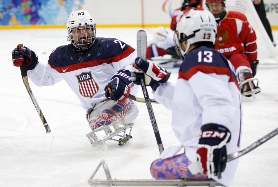 United States's Joshua Pauls, left, celebrates as Joshua Sweeney, right scores a goal during the gold medal ice sledge hockey match between United States and Russia at the 2014 Winter Paralympics in Sochi, Russia, Saturday, March 15, 2014. (AP Photo/Pavel Golovkin)