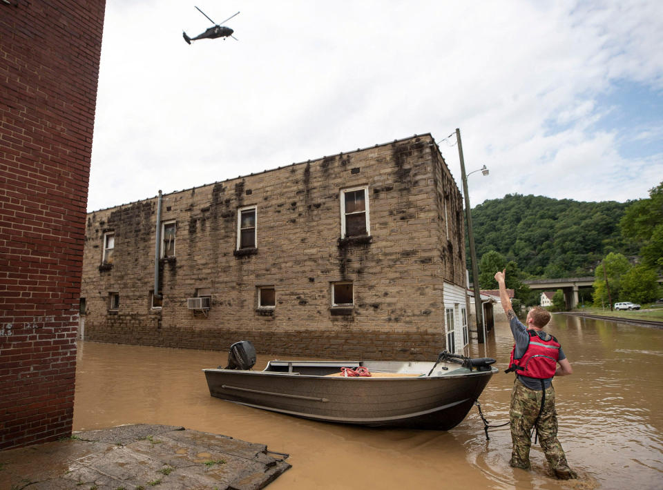 James Jacobs signals to a National Guard helicopter flying overhead following a day of heavy rain in Garrett, Ky., Thursday. 