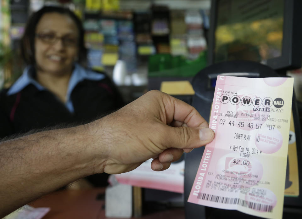 A man holds up a Powerball ticket he purchased Wednesday, Feb. 19, 2014, in Miami. Wednesday's Powerball drawing carries a potential $400 million-plus jackpot. If no one matches all the numbers, the prize potential will grow before the next drawing on Saturday. (AP Photo/Lynne Sladky)